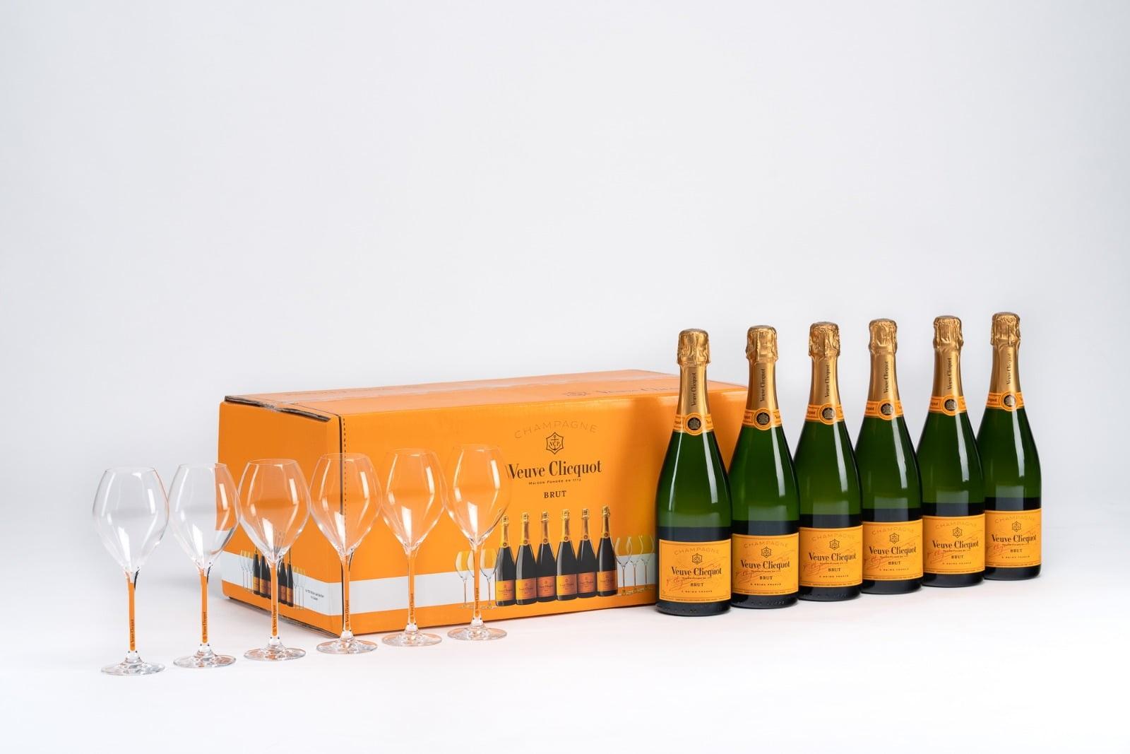 A box of Yellow Lable Brut with six bottles and six glasses in front of it.